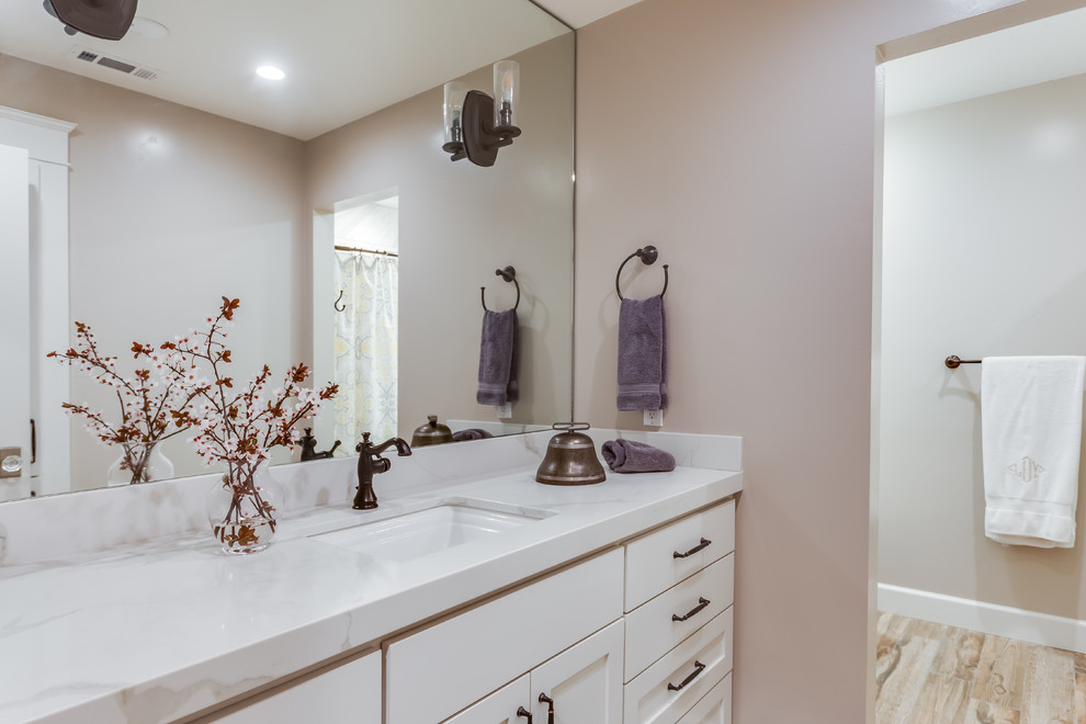 Example of a mid-sized transitional master light wood floor and brown floor bathroom design in Sacramento with shaker cabinets, white cabinets, beige walls, an undermount sink, gray countertops and marble countertops