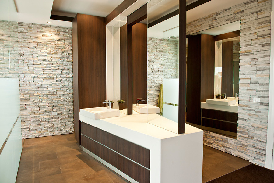 Пример оригинального дизайна: большая главная ванная комната в современном стиле с настольной раковиной, плоскими фасадами, темными деревянными фасадами, столешницей из искусственного кварца, двойным душем, белой плиткой, каменной плиткой, белыми стенами и полом из керамической плитки