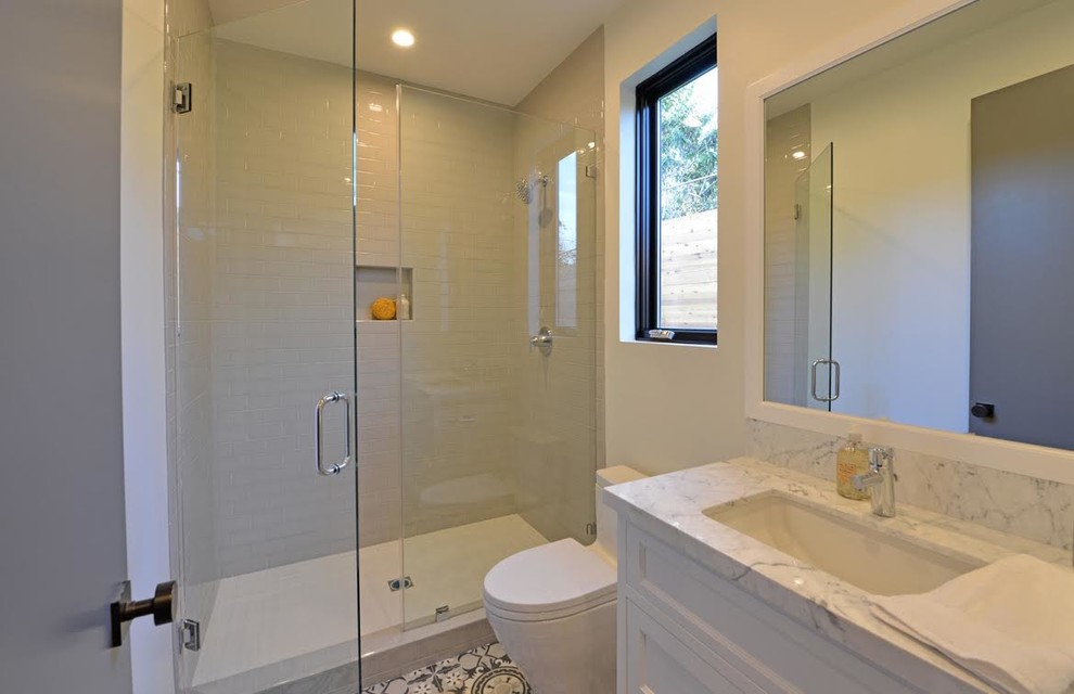 Medium sized contemporary shower room bathroom in Los Angeles with recessed-panel cabinets, white cabinets, an alcove shower, a one-piece toilet, white tiles, marble tiles, white walls, cement flooring, a submerged sink, marble worktops, white floors and a hinged door.