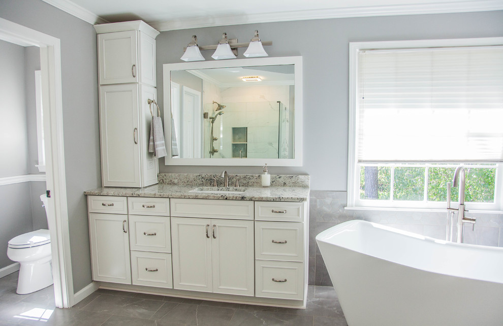 Example of a large trendy master gray tile and porcelain tile ceramic tile and gray floor bathroom design in Atlanta with shaker cabinets, white cabinets, a two-piece toilet, gray walls, an undermount sink, granite countertops, a hinged shower door and white countertops