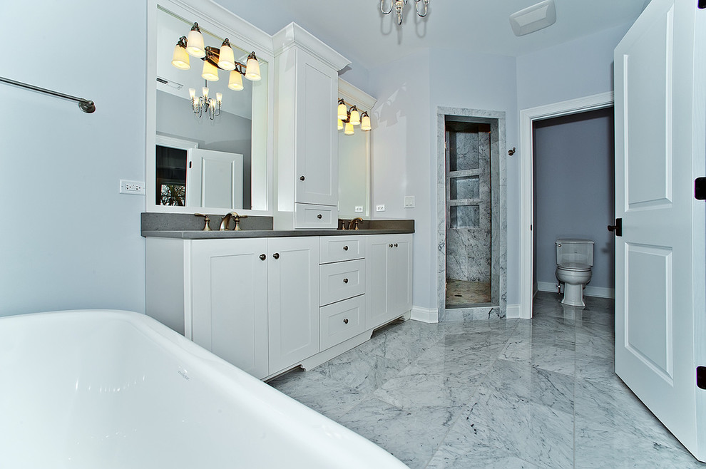 Cette photo montre une salle de bain principale chic de taille moyenne avec un placard à porte shaker, des portes de placard blanches, une baignoire indépendante, un mur gris, un sol en marbre, un lavabo encastré, un plan de toilette en stéatite, un sol gris et un plan de toilette gris.