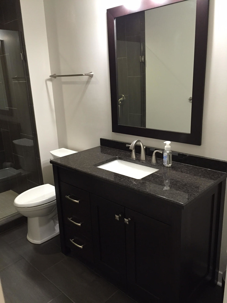 Exempel på ett mellanstort klassiskt svart svart badrum med dusch, med släta luckor, svarta skåp, en dusch i en alkov, en toalettstol med hel cisternkåpa, grå kakel, beige väggar, skiffergolv, ett undermonterad handfat, granitbänkskiva, svart golv och dusch med gångjärnsdörr