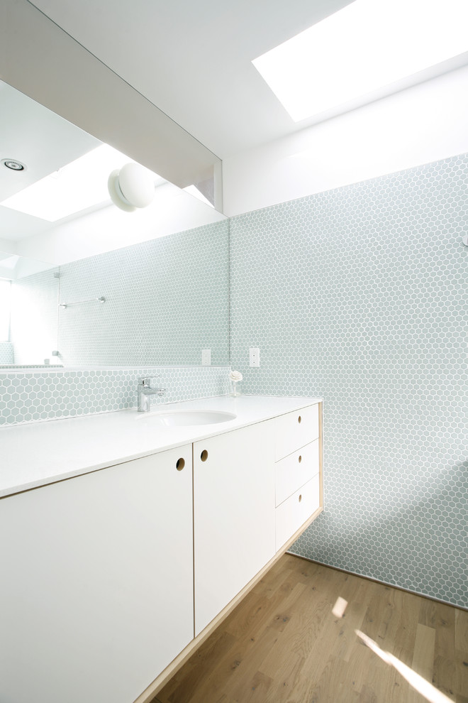 Modelo de cuarto de baño escandinavo con armarios con paneles lisos, puertas de armario blancas, baldosas y/o azulejos azules y baldosas y/o azulejos en mosaico