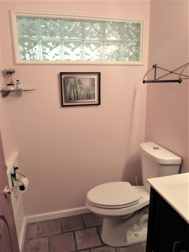Aménagement d'une petite salle d'eau campagne en bois foncé avec un placard à porte plane, WC séparés, un mur rose, tomettes au sol et un plan de toilette en surface solide.