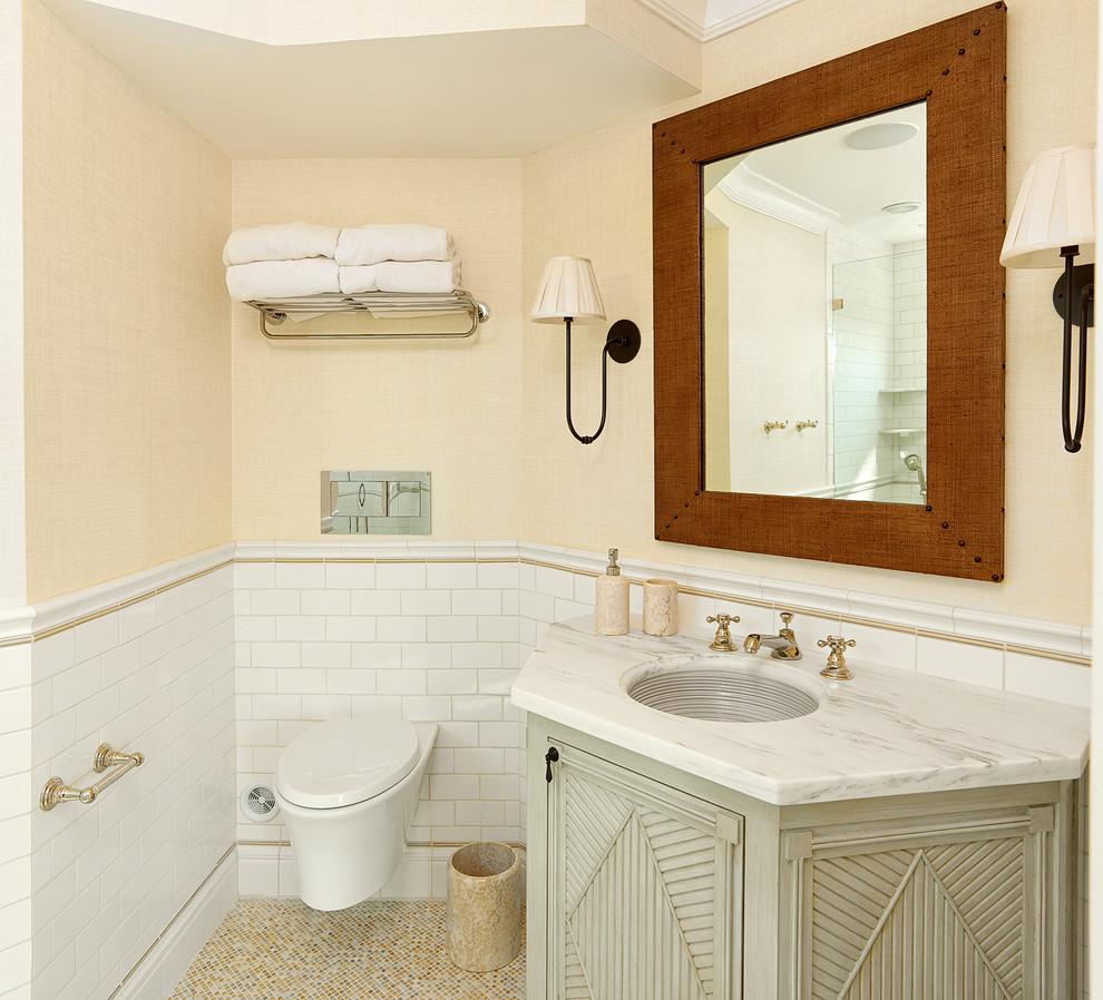 Diseño de cuarto de baño tradicional renovado con lavabo bajoencimera, armarios tipo mueble, encimera de mármol, sanitario de pared, baldosas y/o azulejos blancos y baldosas y/o azulejos de cemento