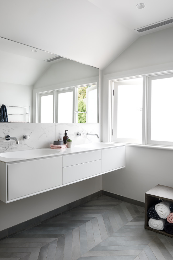 Inspiration pour une salle de bain design de taille moyenne avec des portes de placard blanches, une douche d'angle, WC à poser, un carrelage gris, des carreaux de porcelaine, un mur blanc, un sol en carrelage de porcelaine, un lavabo intégré et un plan de toilette en surface solide.
