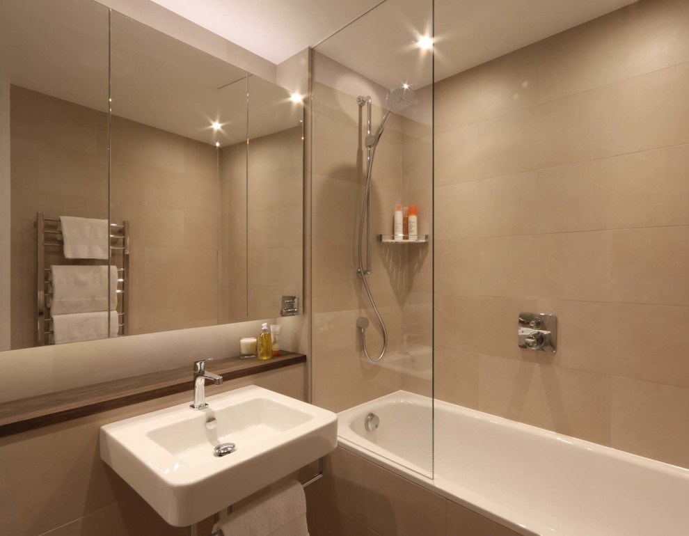 Medium sized contemporary bathroom in London with a wall-mounted sink, flat-panel cabinets, wooden worktops, a built-in bath, a one-piece toilet, beige tiles, porcelain tiles, beige walls and porcelain flooring.