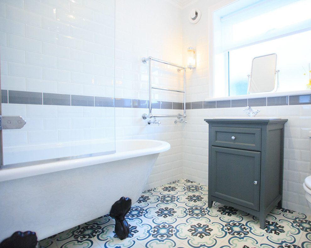 На фото: маленькая детская ванная комната в классическом стиле с фасадами в стиле шейкер, серыми фасадами, ванной на ножках, душем над ванной, унитазом-моноблоком, белой плиткой, белыми стенами, полом из цементной плитки, монолитной раковиной, столешницей из искусственного кварца, разноцветным полом и душем с распашными дверями для на участке и в саду