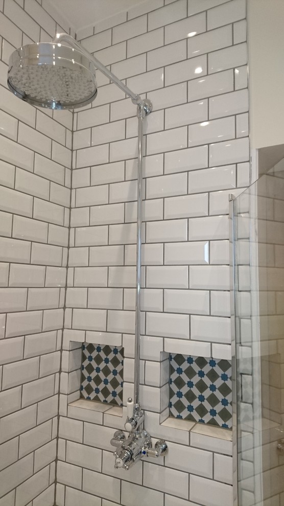 Inredning av ett klassiskt litet badrum, med luckor med upphöjd panel, ett platsbyggt badkar, en dusch i en alkov, vit kakel, tunnelbanekakel, vita väggar och klinkergolv i keramik