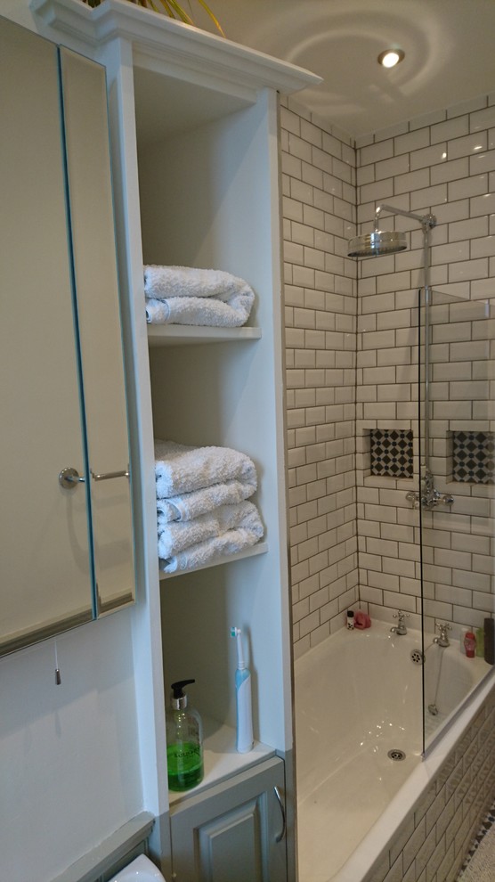 Modelo de cuarto de baño tradicional pequeño con armarios con paneles con relieve, bañera encastrada, ducha empotrada, baldosas y/o azulejos blancos, baldosas y/o azulejos de cemento, paredes blancas y suelo de baldosas de cerámica