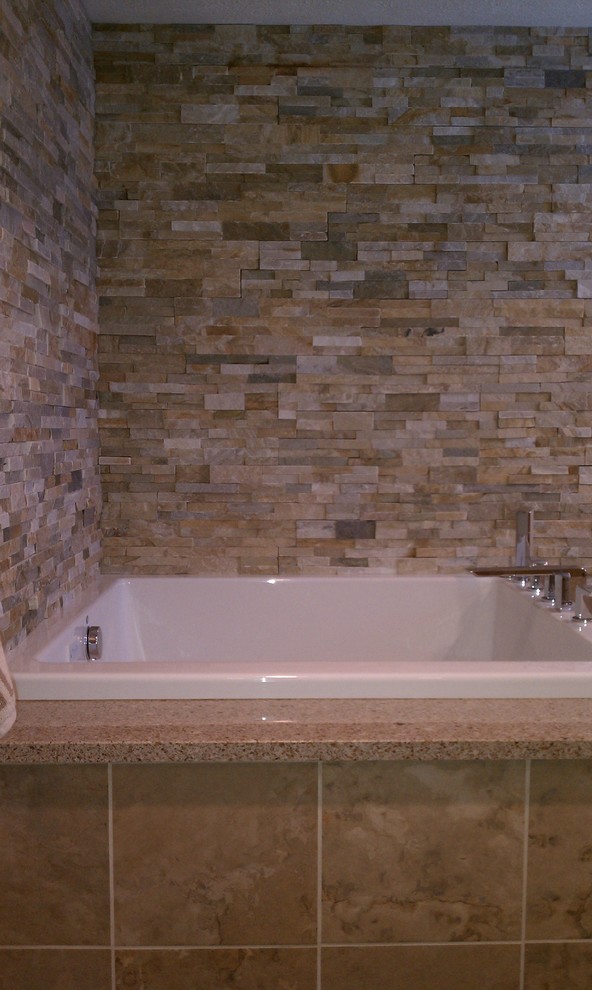 На фото: главная ванная комната среднего размера в современном стиле с светлыми деревянными фасадами, угловой ванной, столешницей из гранита, бежевой плиткой и коричневыми стенами с