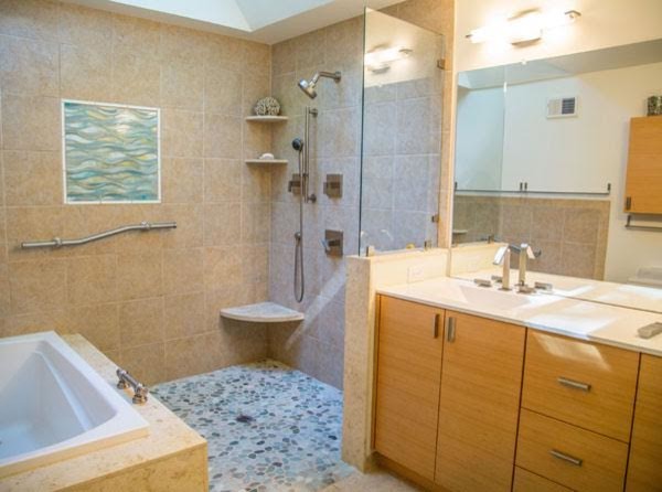 Cette image montre une salle de bain principale marine en bois clair de taille moyenne avec un placard à porte plane, une baignoire posée, une douche ouverte, des carreaux de miroir, un mur beige, un sol en galet, un lavabo encastré, un plan de toilette en surface solide et un sol beige.