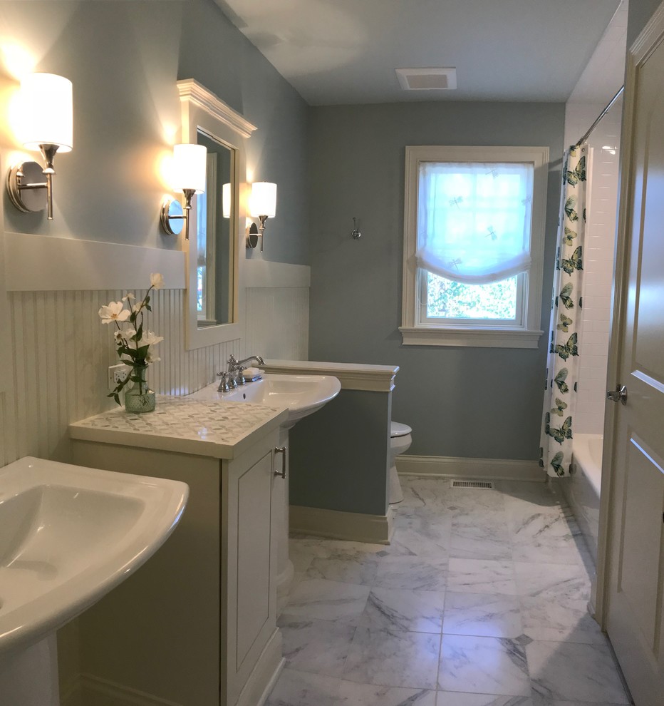 Inredning av ett klassiskt mellanstort badrum för barn, med möbel-liknande, vita skåp, ett badkar i en alkov, en dusch/badkar-kombination, en toalettstol med separat cisternkåpa, vit kakel, keramikplattor, blå väggar, marmorgolv, ett piedestal handfat, kaklad bänkskiva, vitt golv och dusch med duschdraperi