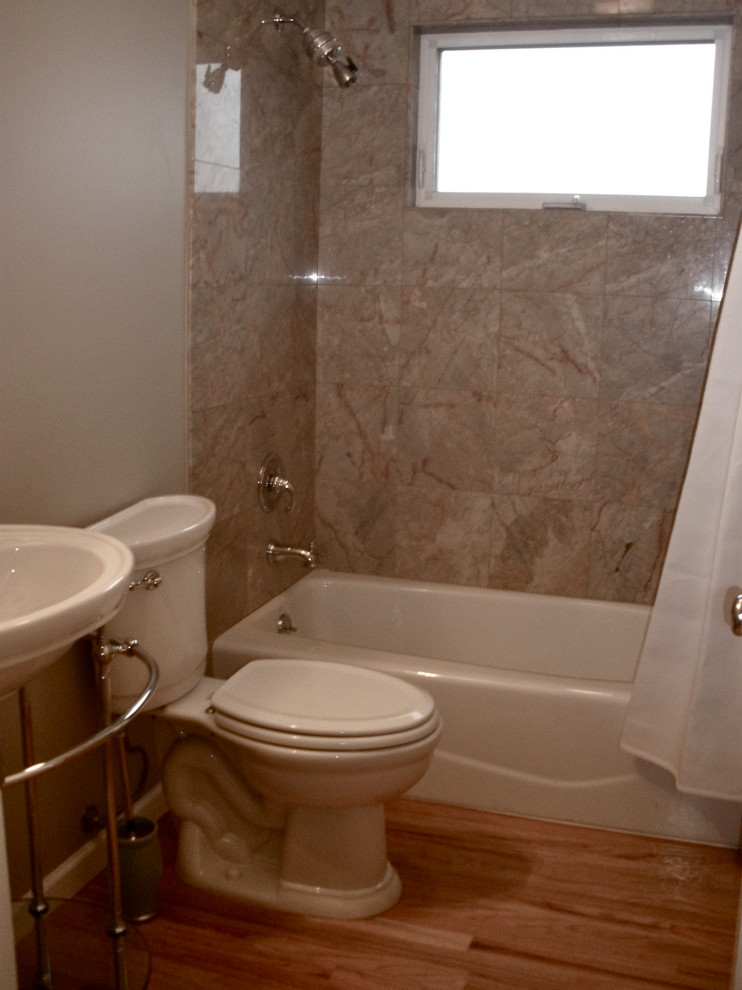 Badezimmer mit Waschtischkonsole, Badewanne in Nische, Duschbadewanne, Wandtoilette mit Spülkasten, Steinfliesen und braunem Holzboden in Seattle