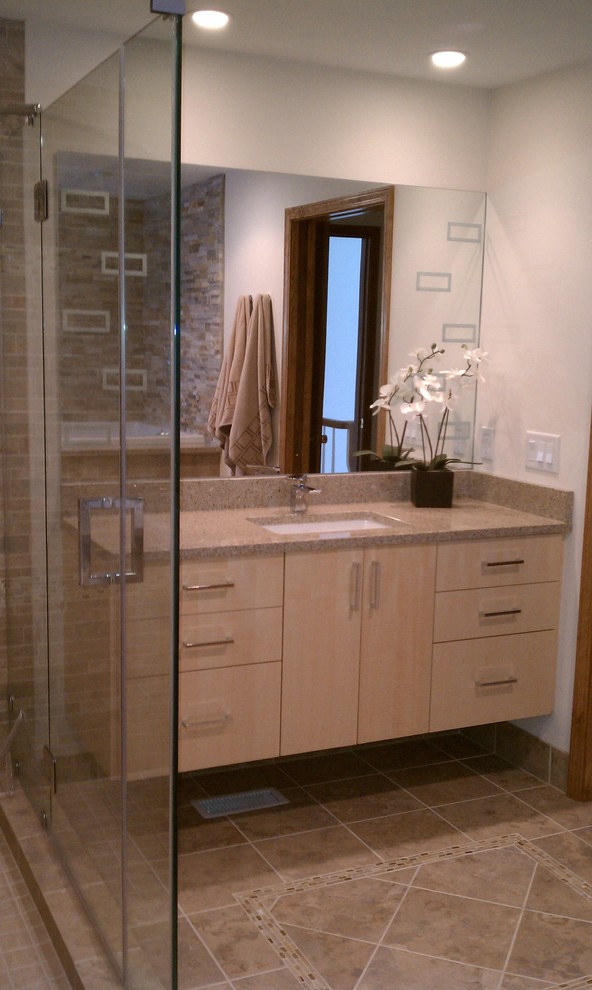 Bild på ett mellanstort funkis badrum med dusch, med ett undermonterad handfat, släta luckor, skåp i ljust trä, granitbänkskiva, en hörndusch, beige kakel och bruna väggar