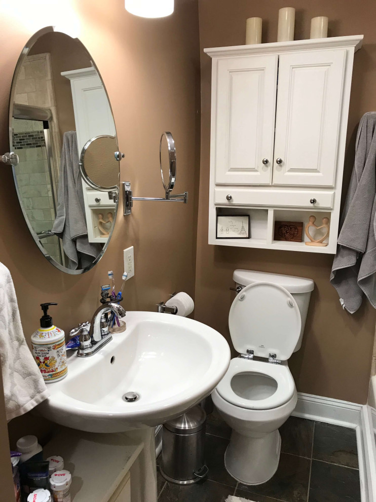 ワシントンD.C.にあるお手頃価格の小さなトランジショナルスタイルのおしゃれなバスルーム (浴槽なし) (白いキャビネット、アンダーマウント型浴槽、シャワー付き浴槽	、一体型トイレ	、ベージュのタイル、ベージュの壁、スレートの床、コンソール型シンク、ガラスの洗面台、茶色い床、引戸のシャワー、白い洗面カウンター、ニッチ、洗面台1つ、造り付け洗面台、パネル壁、磁器タイル、シェーカースタイル扉のキャビネット) の写真