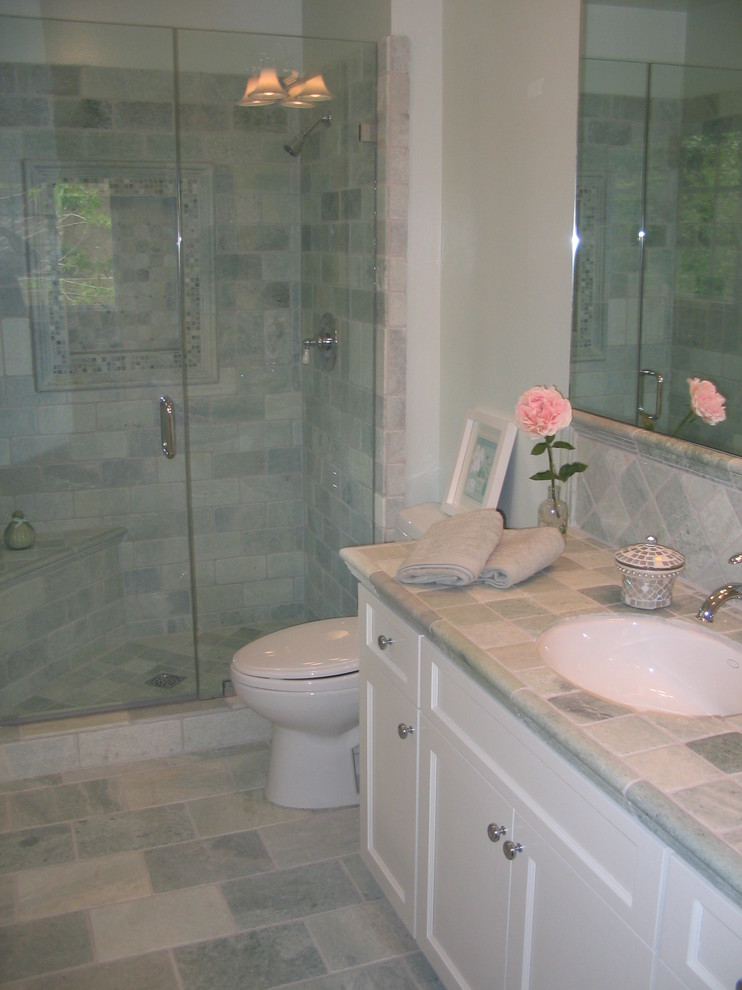 Idee per una stanza da bagno con doccia design di medie dimensioni con lavabo sottopiano, ante in stile shaker, ante bianche, top piastrellato, piastrelle in pietra, pareti verdi, pavimento in travertino e piastrelle grigie