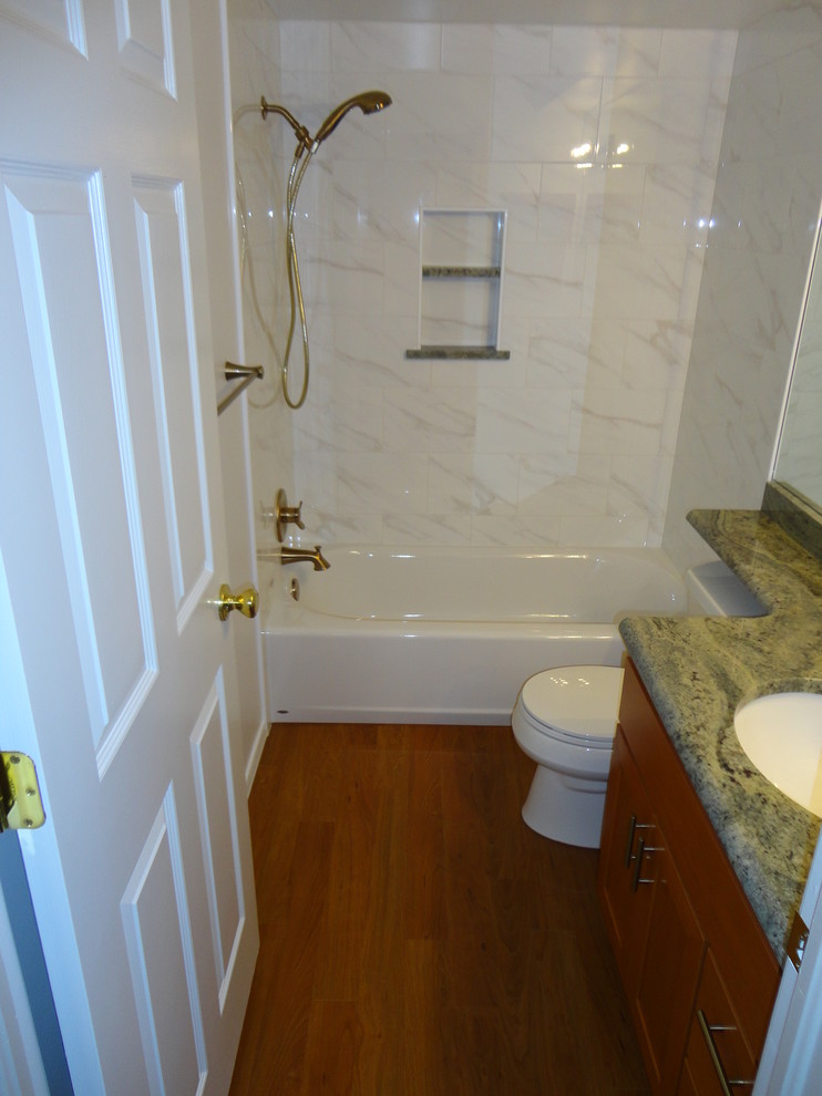 Exempel på ett litet klassiskt en-suite badrum, med skåp i shakerstil, skåp i mellenmörkt trä, ett badkar i en alkov, en dusch/badkar-kombination, en toalettstol med separat cisternkåpa, vit kakel, porslinskakel, vita väggar, vinylgolv, ett undermonterad handfat, granitbänkskiva, brunt golv och dusch med duschdraperi