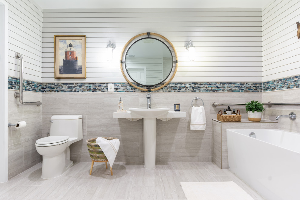 Стильный дизайн: ванная комната в морском стиле с отдельно стоящей ванной, серой плиткой, белыми стенами, раковиной с пьедесталом, серым полом, тумбой под одну раковину и стенами из вагонки - последний тренд