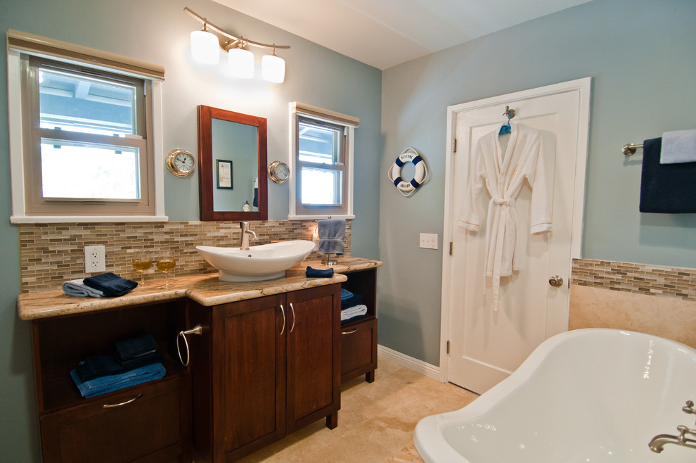 Idées déco pour une salle de bain contemporaine en bois foncé avec un placard à porte shaker, un mur bleu, un sol en calcaire, une vasque et une baignoire sur pieds.