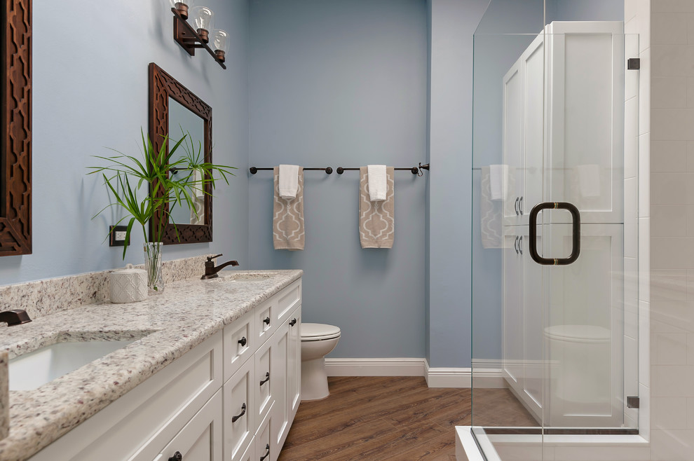 Immagine di una stanza da bagno padronale moderna di medie dimensioni con ante in stile shaker, ante bianche, doccia ad angolo, piastrelle bianche, pareti blu, pavimento con piastrelle in ceramica, pavimento marrone e porta doccia a battente
