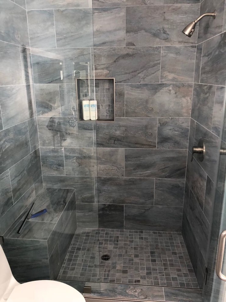Photo of a medium sized nautical bathroom in Los Angeles with shaker cabinets, white cabinets, an alcove shower, a one-piece toilet, grey tiles, blue walls, porcelain flooring, a submerged sink, marble worktops, grey floors, a hinged door and grey worktops.