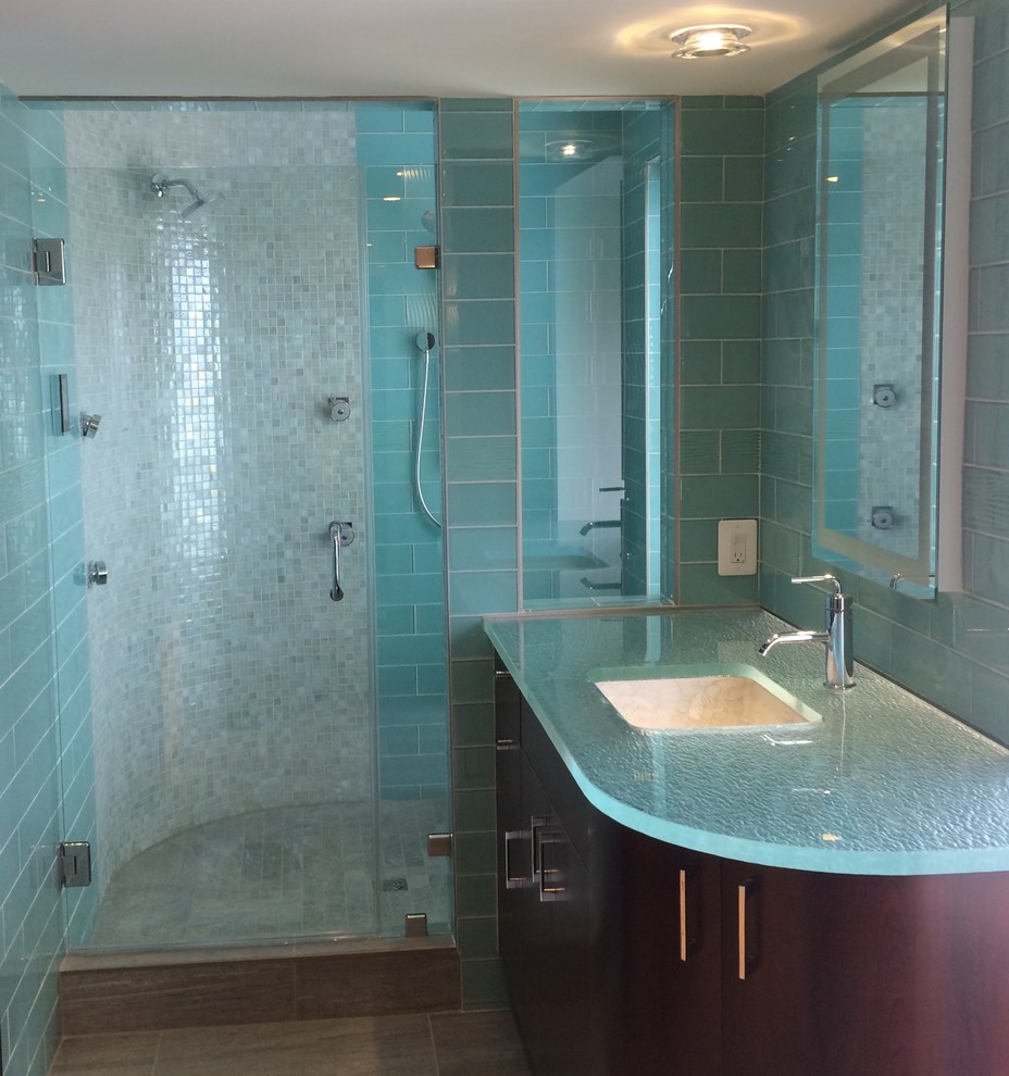Idéer för mellanstora funkis blått badrum med dusch, med en dusch i en alkov, ett undermonterad handfat, släta luckor, skåp i mörkt trä, blå kakel, glaskakel, blå väggar, klinkergolv i porslin, bänkskiva i glas, brunt golv och dusch med gångjärnsdörr