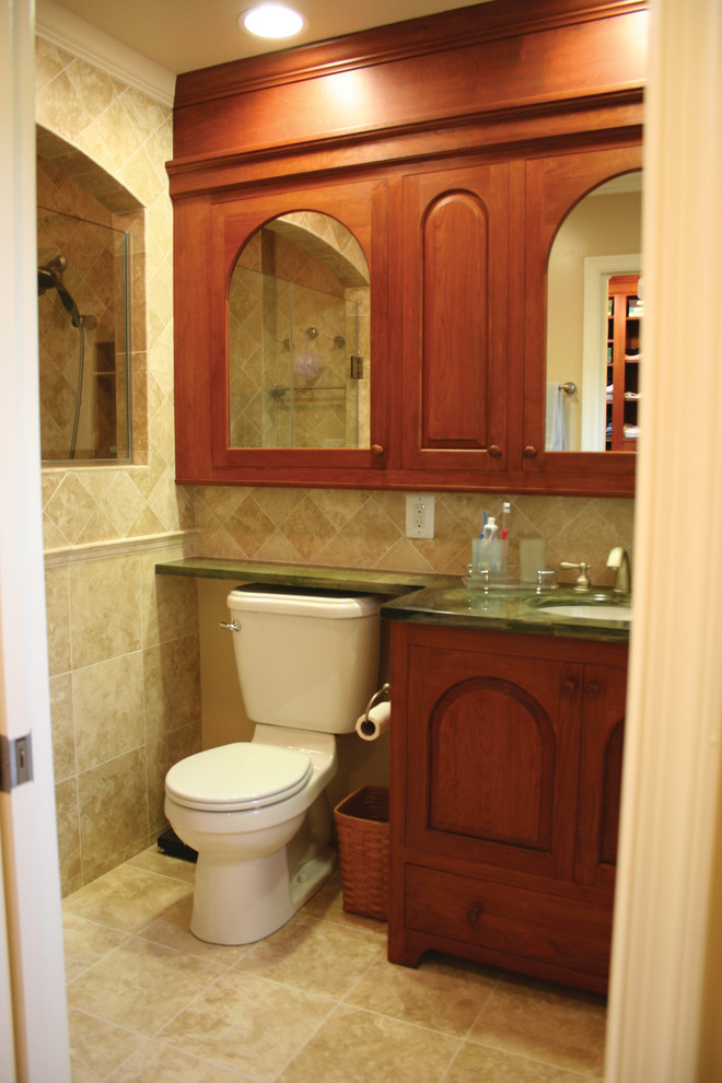 Immagine di una stanza da bagno tradizionale con ante con bugna sagomata, ante in legno scuro, pareti beige e lavabo sottopiano