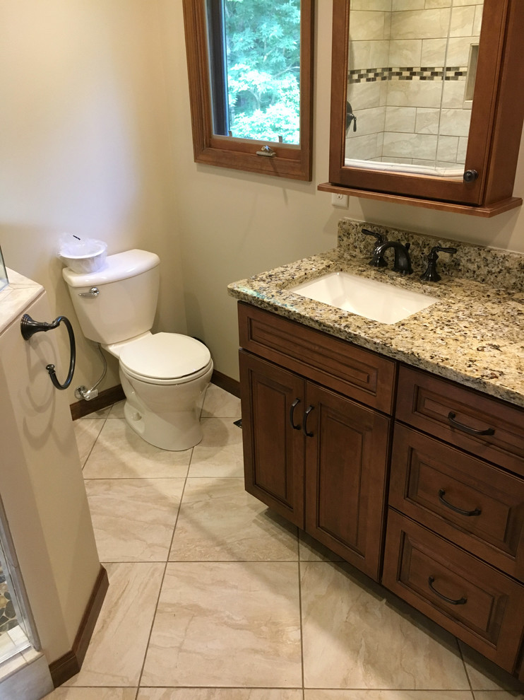 Inspiration for a medium sized traditional ensuite bathroom in Other with raised-panel cabinets, medium wood cabinets, a corner shower, a one-piece toilet, beige walls, ceramic flooring, a submerged sink, granite worktops, beige floors and a hinged door.