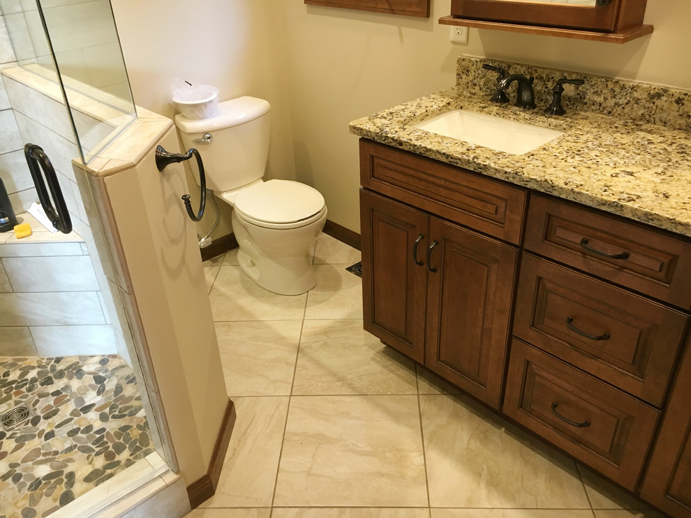 Photo of a medium sized traditional ensuite bathroom in Other with raised-panel cabinets, medium wood cabinets, a corner shower, a one-piece toilet, beige walls, ceramic flooring, a submerged sink, granite worktops, beige floors and a hinged door.