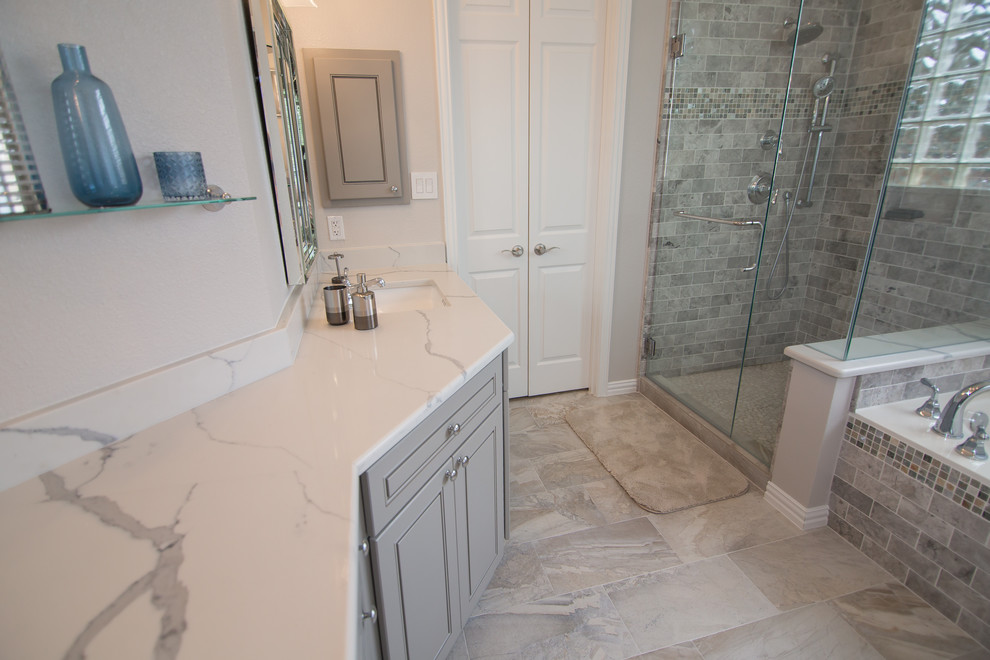 Exemple d'une salle de bain principale éclectique de taille moyenne avec un placard à porte shaker, des portes de placard grises, une baignoire posée, une douche d'angle, WC séparés, un carrelage gris, un carrelage métro, un mur gris, un sol en carrelage de porcelaine, un lavabo encastré, un plan de toilette en quartz modifié, un sol gris, une cabine de douche à porte battante et un plan de toilette blanc.