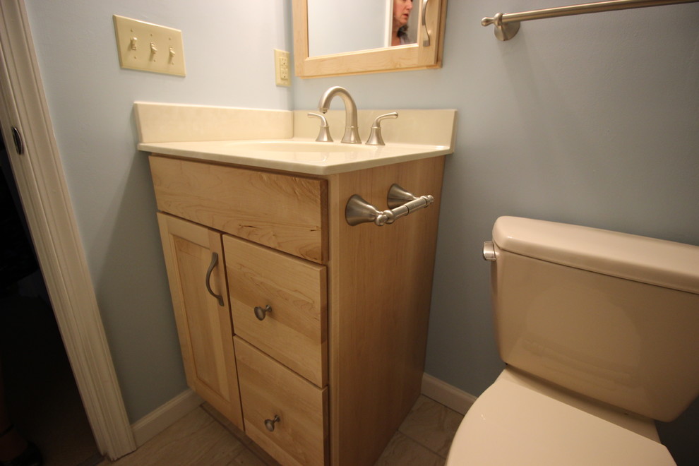 Cette photo montre une petite salle d'eau bord de mer en bois clair avec un placard avec porte à panneau encastré, un combiné douche/baignoire, WC séparés, un carrelage beige, un mur bleu, un sol en carrelage de céramique, un lavabo posé et un plan de toilette en marbre.