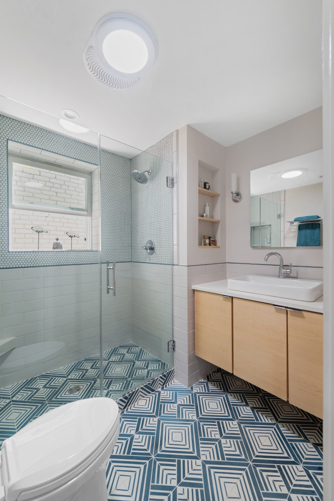 На фото: главная ванная комната среднего размера в стиле фьюжн с светлыми деревянными фасадами, душем в нише, белой плиткой, плиткой кабанчик, белыми стенами, настольной раковиной, столешницей из искусственного кварца, синим полом, душем с распашными дверями, белой столешницей, плоскими фасадами, раздельным унитазом, полом из цементной плитки, сиденьем для душа, тумбой под одну раковину и подвесной тумбой
