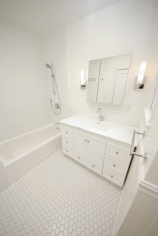 Exempel på ett mellanstort klassiskt en-suite badrum, med ett integrerad handfat, luckor med infälld panel, skåp i ljust trä, bänkskiva i akrylsten, ett badkar i en alkov, en dusch/badkar-kombination, en toalettstol med separat cisternkåpa, vit kakel, keramikplattor, vita väggar och mosaikgolv