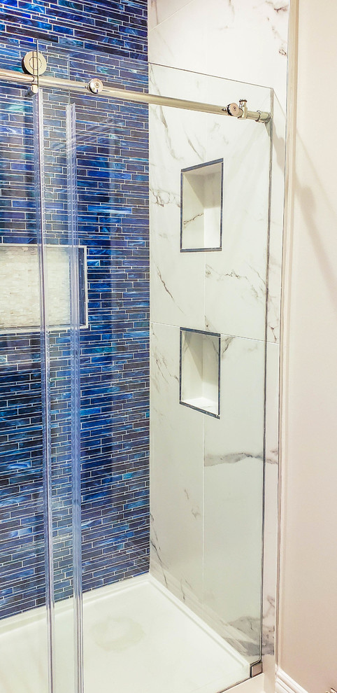 Immagine di una stanza da bagno con doccia chic di medie dimensioni con doccia alcova, porta doccia scorrevole, piastrelle blu e piastrelle di vetro