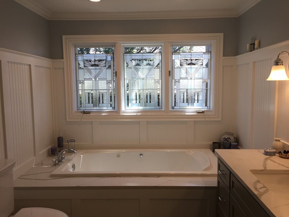 Photo of a medium sized classic ensuite bathroom in Detroit with recessed-panel cabinets, blue cabinets, a built-in bath, a corner shower, grey walls, ceramic flooring, a built-in sink, quartz worktops, grey floors and a hinged door.