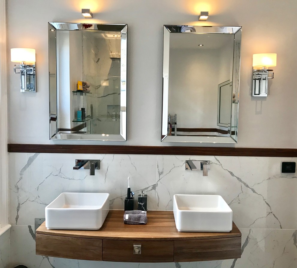 Example of a large trendy master marble floor and gray floor bathroom design in London with furniture-like cabinets, medium tone wood cabinets, a one-piece toilet, a wall-mount sink and wood countertops