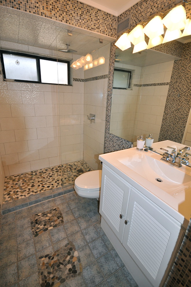 グランドラピッズにある高級な中くらいなトランジショナルスタイルのおしゃれなバスルーム (浴槽なし) (一体型シンク、ルーバー扉のキャビネット、白いキャビネット、人工大理石カウンター、オープン型シャワー、壁掛け式トイレ、マルチカラーのタイル、磁器タイル、白い壁、磁器タイルの床) の写真