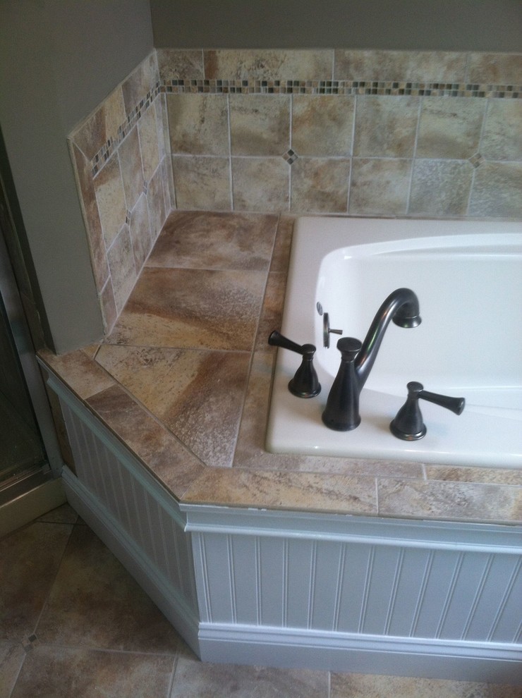 Aménagement d'une salle de bain avec une baignoire posée, un carrelage beige et des carreaux de céramique.