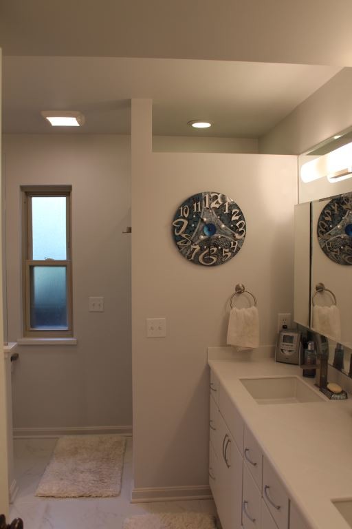 Diseño de cuarto de baño actual con lavabo bajoencimera, puertas de armario blancas y encimera de acrílico