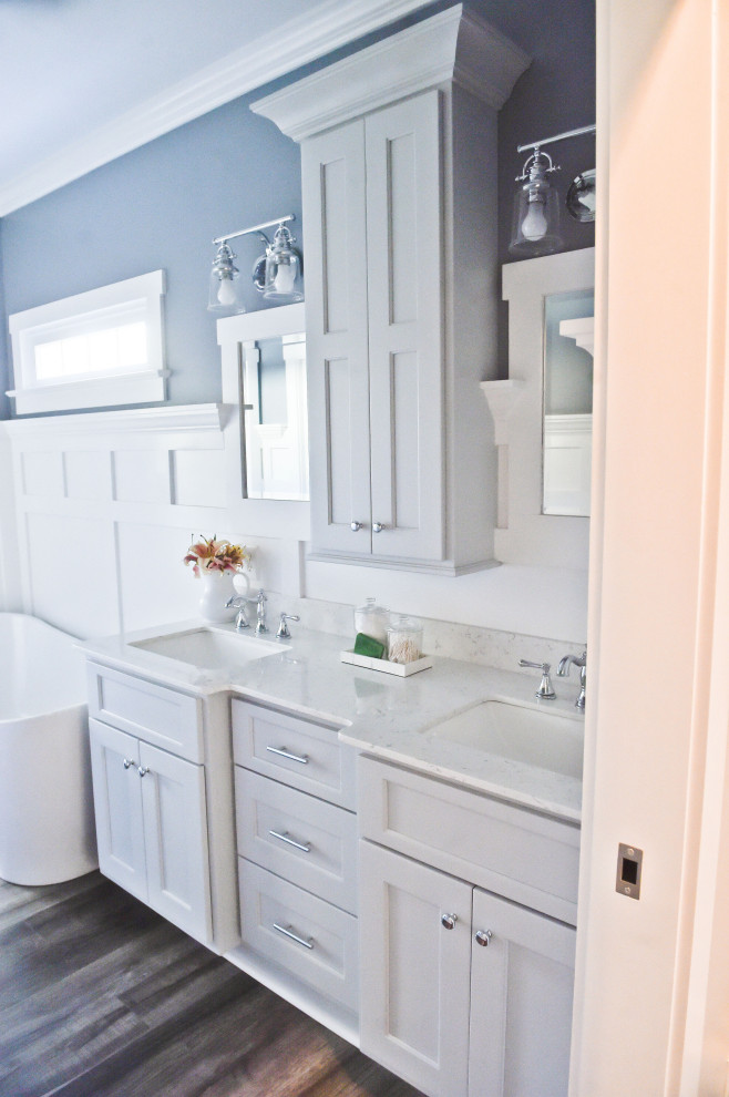 Inspiration pour une salle de bain principale craftsman avec un placard à porte shaker, des portes de placard grises, une baignoire indépendante, un mur bleu, un sol en vinyl, un plan de toilette en marbre, une cabine de douche à porte battante et un plan de toilette blanc.