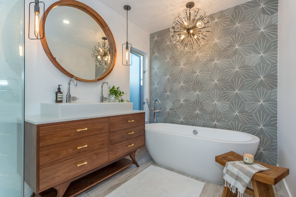 Réalisation d'une grande salle de bain principale design en bois brun avec une baignoire indépendante, un placard à porte plane, un mur gris et une vasque.