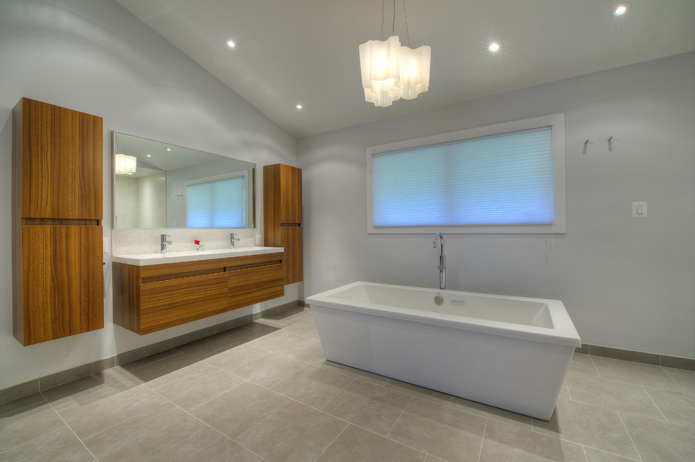 Asiatisk inredning av ett mellanstort en-suite badrum, med ett väggmonterat handfat, släta luckor, skåp i mellenmörkt trä, ett fristående badkar, en öppen dusch, en vägghängd toalettstol och grå väggar