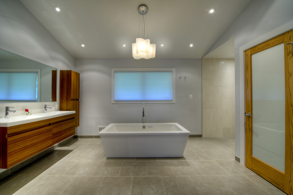 Inredning av ett asiatiskt en-suite badrum, med ett väggmonterat handfat, släta luckor, skåp i mellenmörkt trä, ett fristående badkar, en öppen dusch, en vägghängd toalettstol, grå kakel och grå väggar