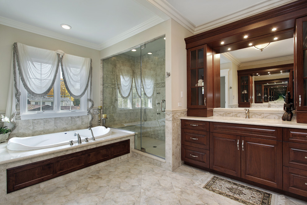 Inspiration for a large timeless master beige tile and stone tile porcelain tile bathroom remodel in Los Angeles with shaker cabinets, dark wood cabinets, a hot tub, beige walls, an undermount sink and marble countertops