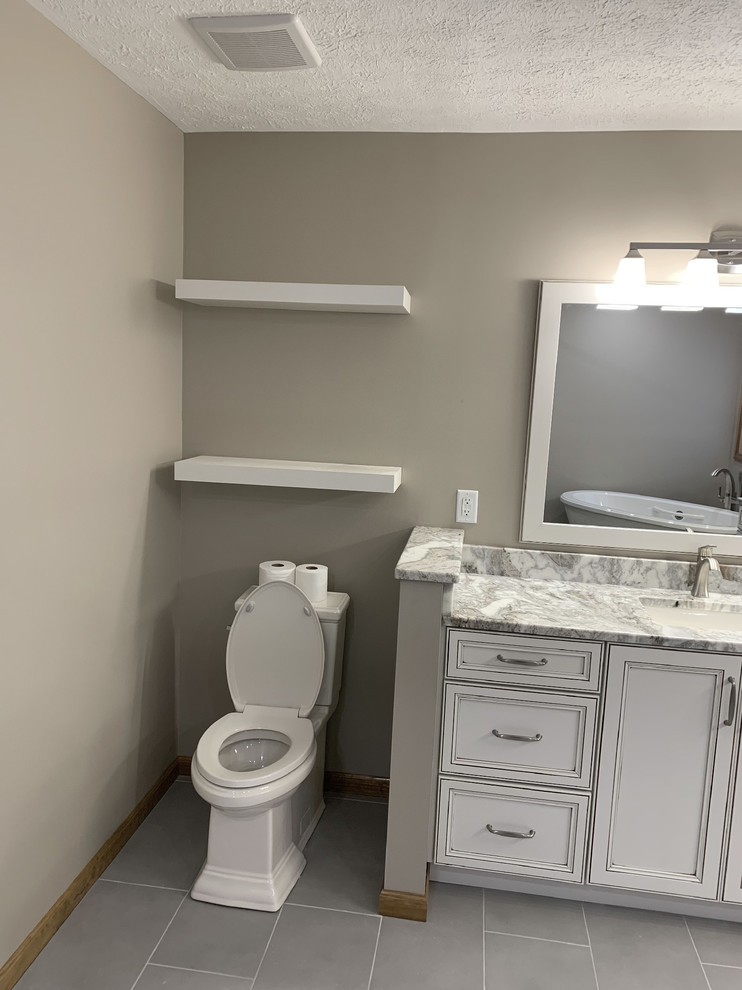 Klassisk inredning av ett stort flerfärgad flerfärgat en-suite badrum, med luckor med infälld panel, vita skåp, ett fristående badkar, en hörndusch, en toalettstol med separat cisternkåpa, beige väggar, klinkergolv i keramik, ett undermonterad handfat, grått golv och dusch med gångjärnsdörr