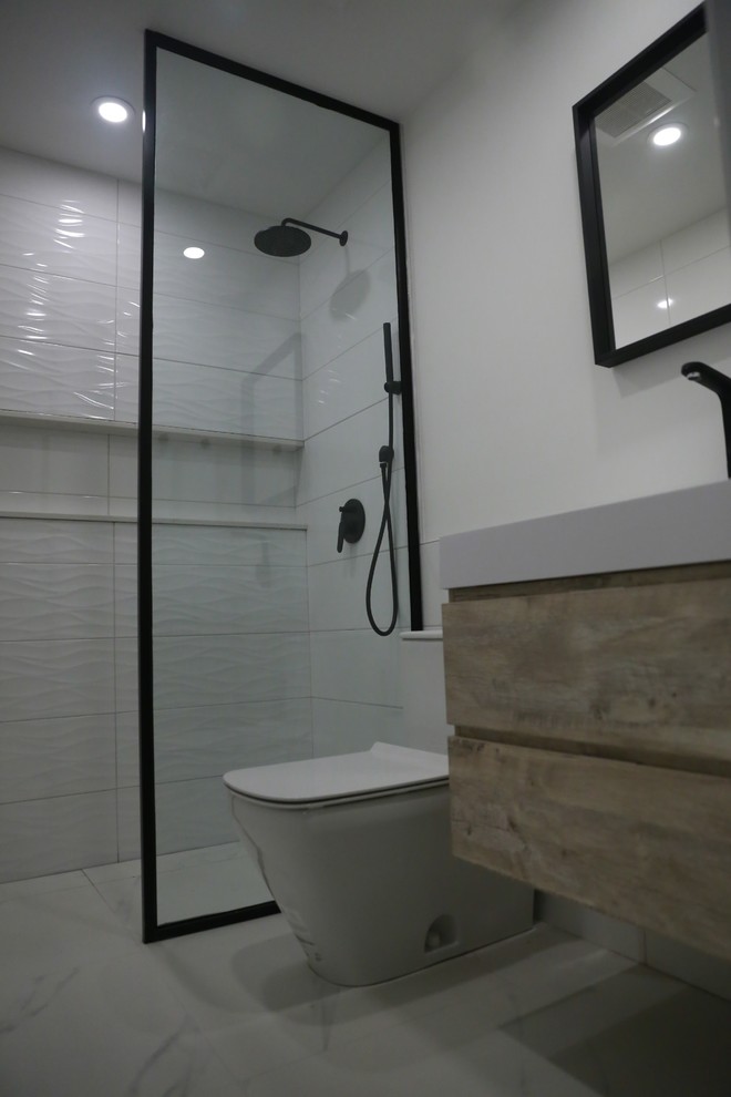 Imagen de cuarto de baño contemporáneo pequeño con puertas de armario de madera clara, ducha a ras de suelo, sanitario de una pieza, paredes blancas, suelo de baldosas de porcelana, aseo y ducha, suelo blanco y ducha abierta