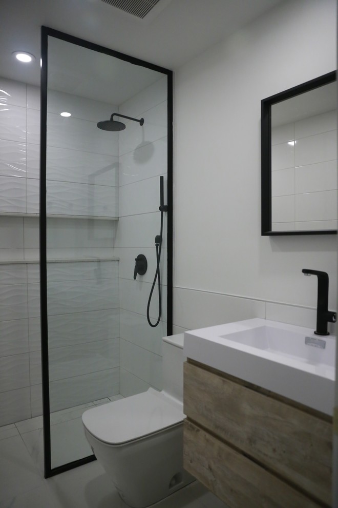 Ejemplo de cuarto de baño actual pequeño con puertas de armario de madera clara, ducha a ras de suelo, sanitario de una pieza, paredes blancas, suelo de baldosas de porcelana, aseo y ducha, suelo blanco y ducha abierta