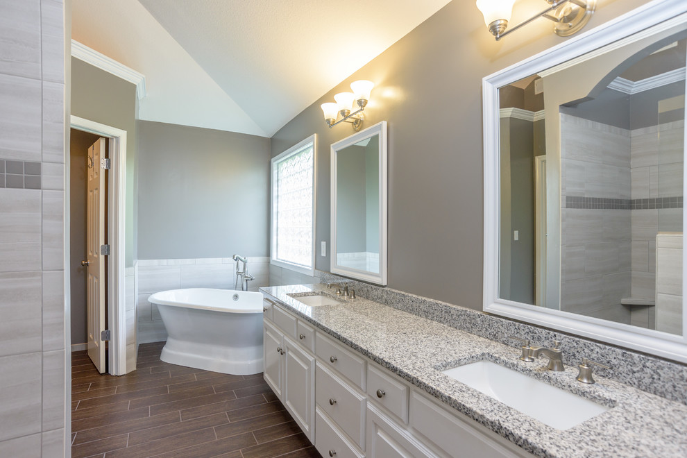 Foto på ett mellanstort vintage en-suite badrum, med grå väggar, klinkergolv i porslin, ett undermonterad handfat, brunt golv, luckor med upphöjd panel, vita skåp, ett fristående badkar, en dusch i en alkov, grå kakel, porslinskakel, bänkskiva i terrazo och med dusch som är öppen