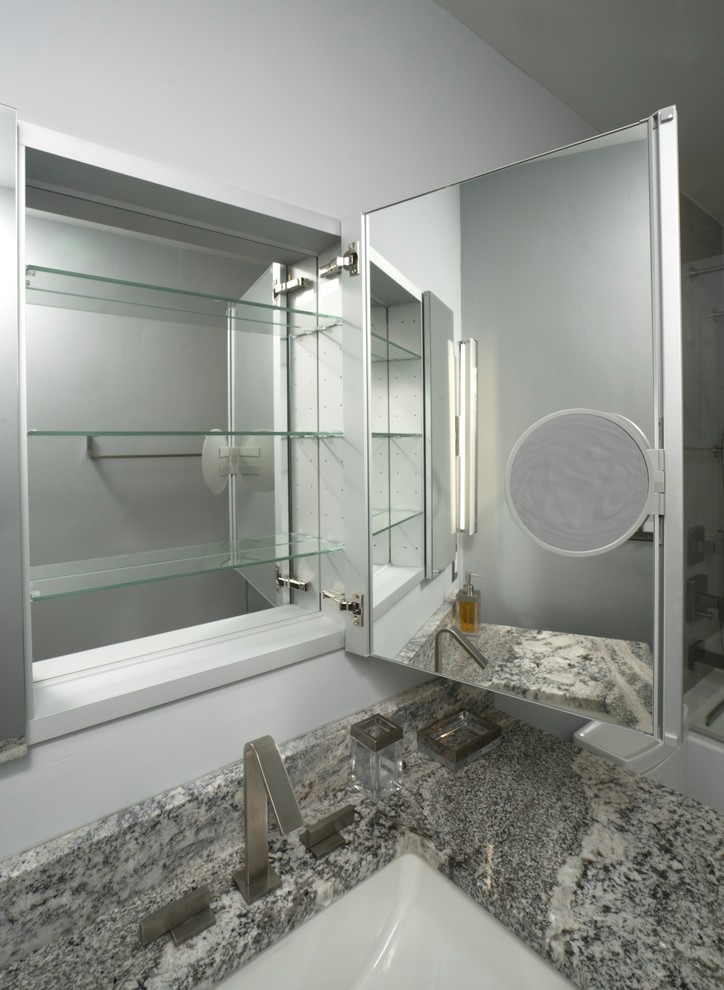 Design ideas for a small contemporary bathroom in DC Metro with flat-panel cabinets, medium wood cabinets, a shower/bath combination, a wall mounted toilet, grey tiles, porcelain tiles, blue walls, porcelain flooring, a submerged sink, granite worktops, grey floors, a hinged door and grey worktops.